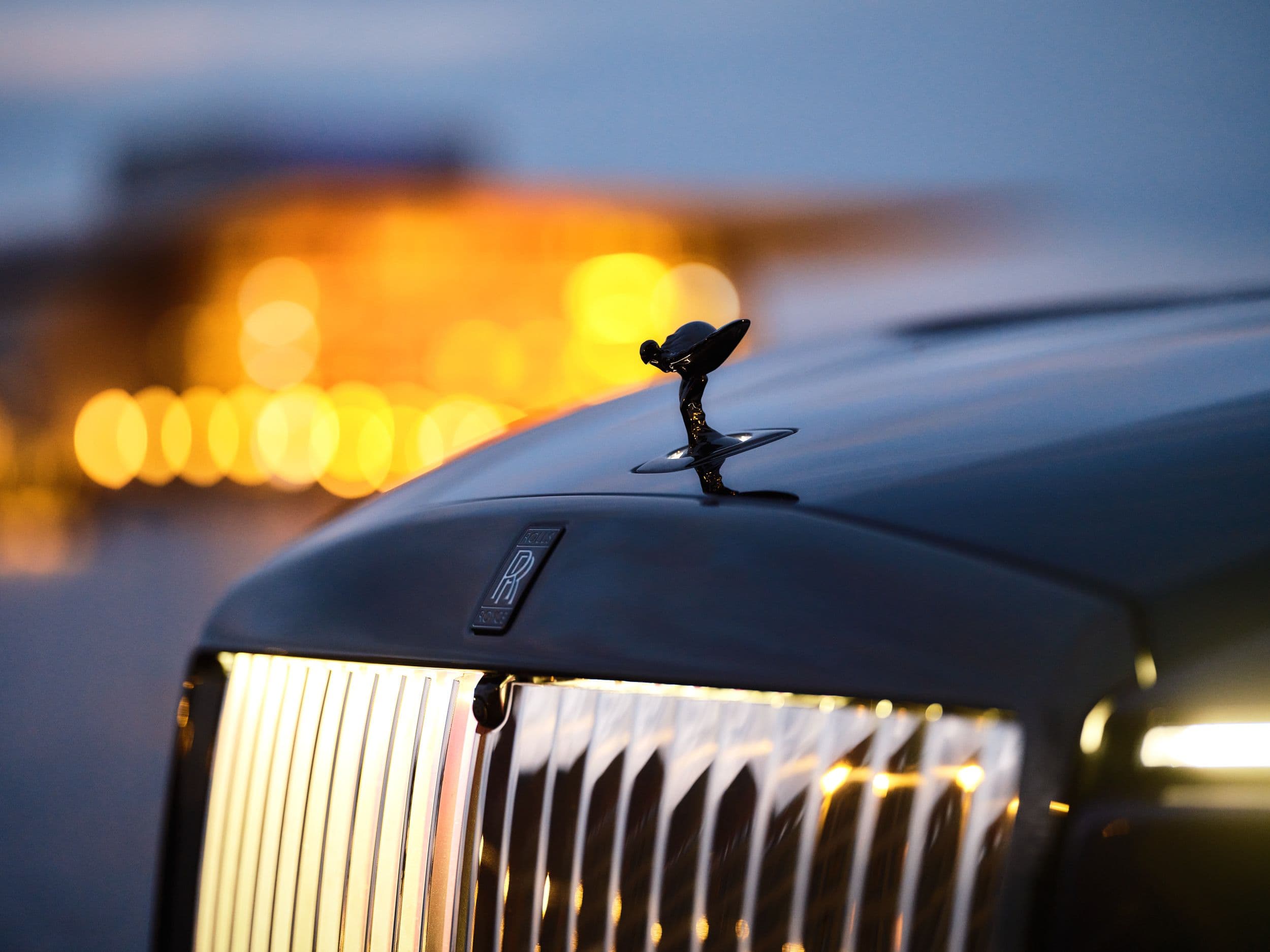 Close-up of a Rolls-Royce hood ornament, the Spirit of Ecstasy, at dusk.